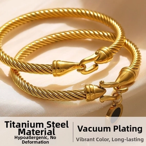 Detail of 18k gold plated cable bangles with Roman numeral pendant on white silk background