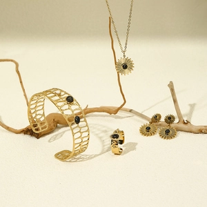 Golden bohemian jewelry set featuring sunburst patterns and black gemstones on sand