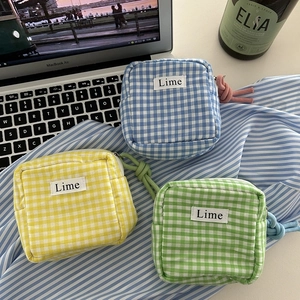 Three colorful checkered canvas pouches in blue, yellow, and green for makeup or storage