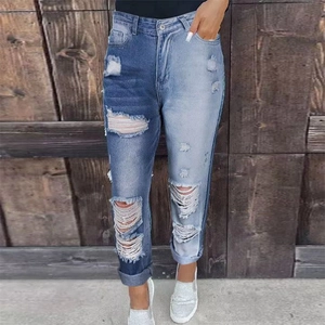 Dettaglio di jeans patchwork blu con ginocchia strappate e orlo sfrangiato