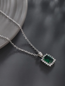 Detailed shot of silver square pendant with green zircon gemstone and fine chain necklace