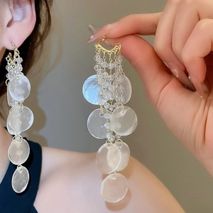 Détail de boucles d'oreilles à franges avec perles en verre et pendentifs nacrés