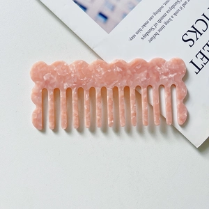 Close-up of pink marble pattern acetate hair comb with wavy teeth on a magazine