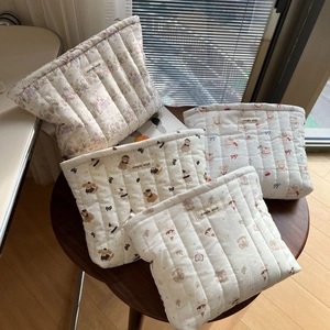 Quilted cotton cosmetic bags with cute animal prints on a rustic wooden stool