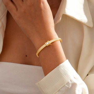 Detail of 18K gold plated bangle featuring a central diamond and pave-set accents on model