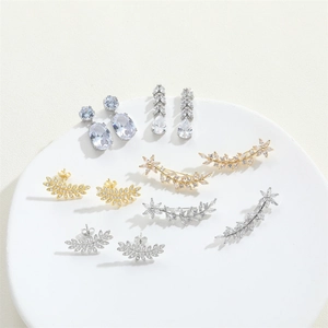 Macro view of zircon-studded leaf and floral earrings in gold and silver finishes