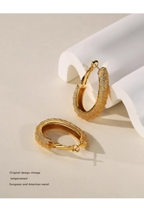 Detail view of gold matte geometric circle earrings on a minimalist decorative background