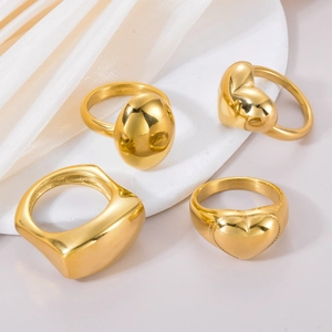 Group of four elegant gold-finished stainless steel rings with heart and oval shapes