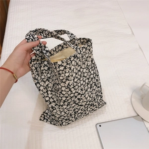 Close-up of a black and white floral canvas tote bag held against a white quilted background