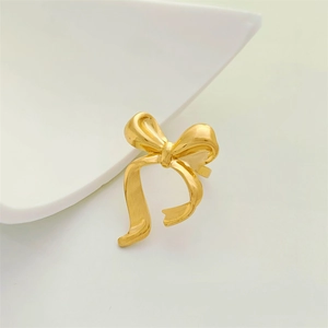 Close-up of matte gold bow ring with vintage pleated texture on a ceramic plate