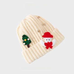 Close-up of cream knit Christmas hat with embroidered trees and festive doll character