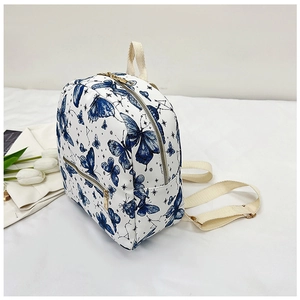 Detailed side view of butterfly print backpack with golden zippers and beige straps