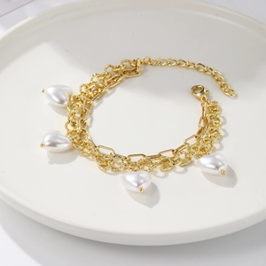 Detail of a vintage golden chain bracelet with four elegant heart-shaped pearl charms