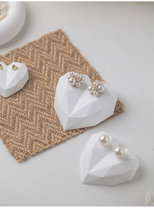 Detail showing elegant pearl and gold heart earrings on heart-shaped display stands