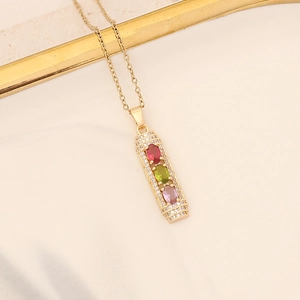 Detail of gold necklace pendant with colorful oval gemstones and small clear crystals