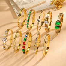 Close-up of golden bracelets featuring colorful emerald, ruby, and zircon gemstone inlays