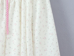 Détail du tissu en mousseline florale avec points suisses et ruban à carreaux rose
