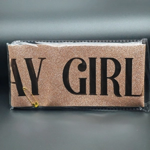 Detail of rose gold glitter sash with AY GIRL text and gold safety pin in packaging