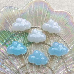 Macro shot of shimmering resin cloud charms in blue and white on a glass plate