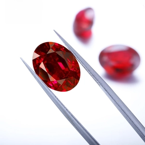Macro shot of an oval-cut lab-grown pigeon blood ruby held by precision metal tweezers