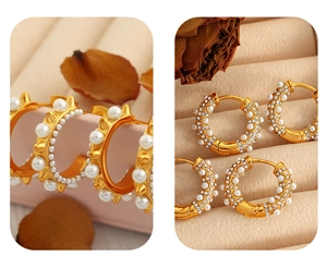 Detail of gold C-shaped hoop earrings with pearls and rhinestones on beige tray