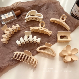 Matte cream hair claws set in floral and geometric shapes on a vintage brown background