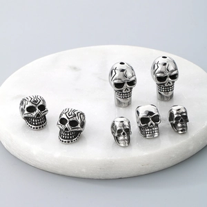 Vintage silver skull beads for DIY jewelry making on a white marble display stand