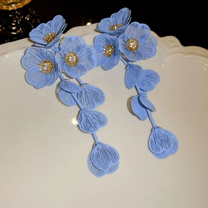 Détail de boucles d'oreilles fleurs bleu clair avec pompons et cristaux brillants