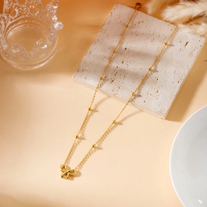 Detail of elegant gold bow pendant necklace with bead chain on decorative stone base