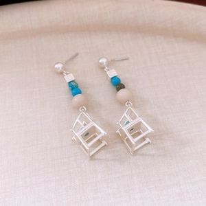Detail of silver pearl stud earrings featuring unique chair pendants and colorful beads