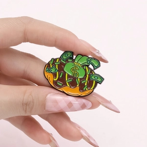 Handheld photo of creative donut and money bag enamel pin with dollar bills and coins