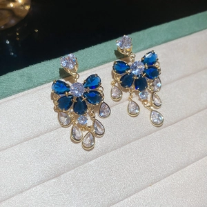 Close-up of golden drop earrings with blue marquise stones and sparkling tassels