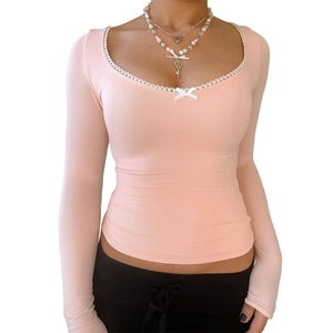 Detail of square neckline with delicate white lace trim and bow on pink slim-fit top