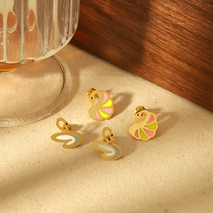 Boucles d'oreilles cygne en émail coloré en acier inoxydable doré sur fond en lin naturel
