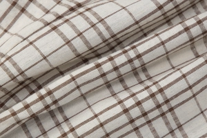 Close-up detail of beige and brown plaid fabric texture with natural fiber weave