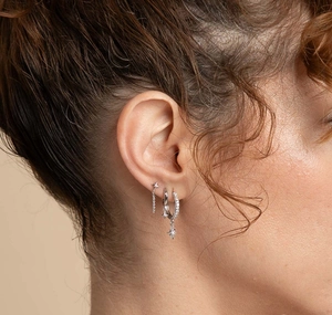 Detailed close-up of S925 silver star pendant earrings with pavé crystals on ear