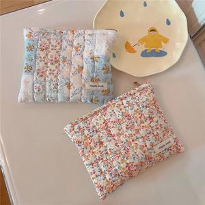 Close-up of quilted floral cotton pouches with zipper closure and brand label