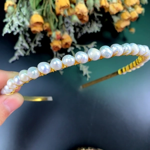 Eleganter Gold-Haarreif mit einer Reihe natürlicher weißer Perlen auf schmalem Rahmen