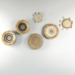 Detail of six woven straw wall hangings with bohemian geometric patterns and tassels