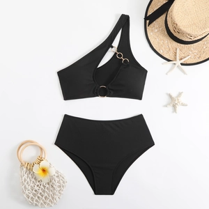 Flat lay of black one-shoulder bikini with gold ring detail and beach accessories