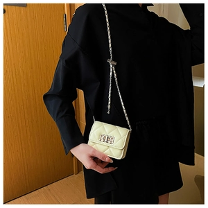 Detail of a beige quilted mini bag with silver chain strap and square metal lock