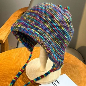 Detailed close-up of bohemian colorful mixed knit earflap hat with decorative braided ties