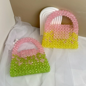 Detail of handmade beaded handbags in pink, yellow and green with top handles and flap design