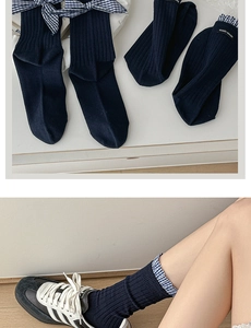Detailed navy knit socks with blue plaid trim and delicate bow accent on cotton texture
