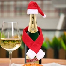 Mini red Christmas hat and scarf set decorating a wine bottle on a festive dinner table