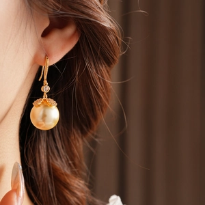 Gros plan de boucles d'oreilles feuille d'or et perle avec zircons sur un mannequin