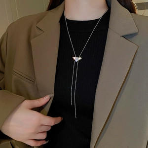Detail of a silver Y-shaped sweater necklace with a pavé diamond triangle pendant