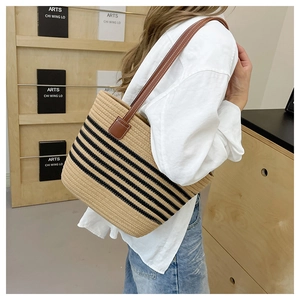 Dettaglio della borsa tote a righe con spalline in pelle marrone indossata a spalla