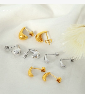 Minimalist gold and silver teardrop earrings displayed on a soft white linen fabric background