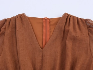 Detail of caramel pleated dress featuring a V-neck back and a seamless invisible zipper